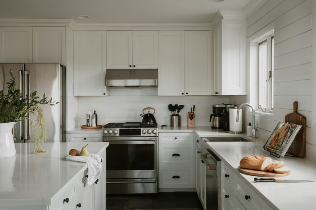White Shaker farmhouse kitchen with black cup pulls, shiplap wall and stainless range