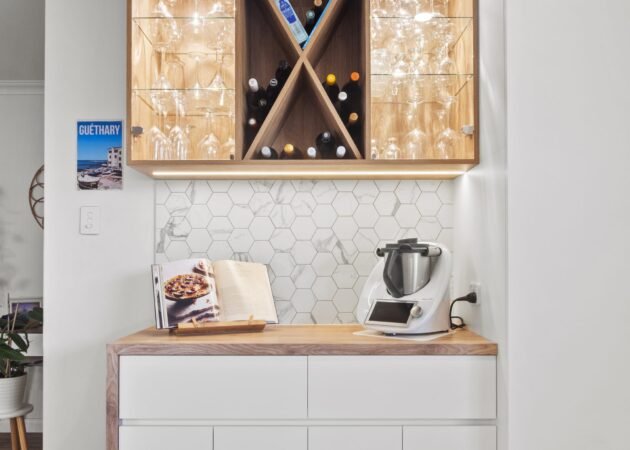 The bar nook: cross wine rack with lit glass shelves over a white cabinet with a timber top