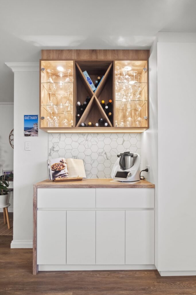 The bar nook: cross wine rack with lit glass shelves over a white cabinet with a timber top