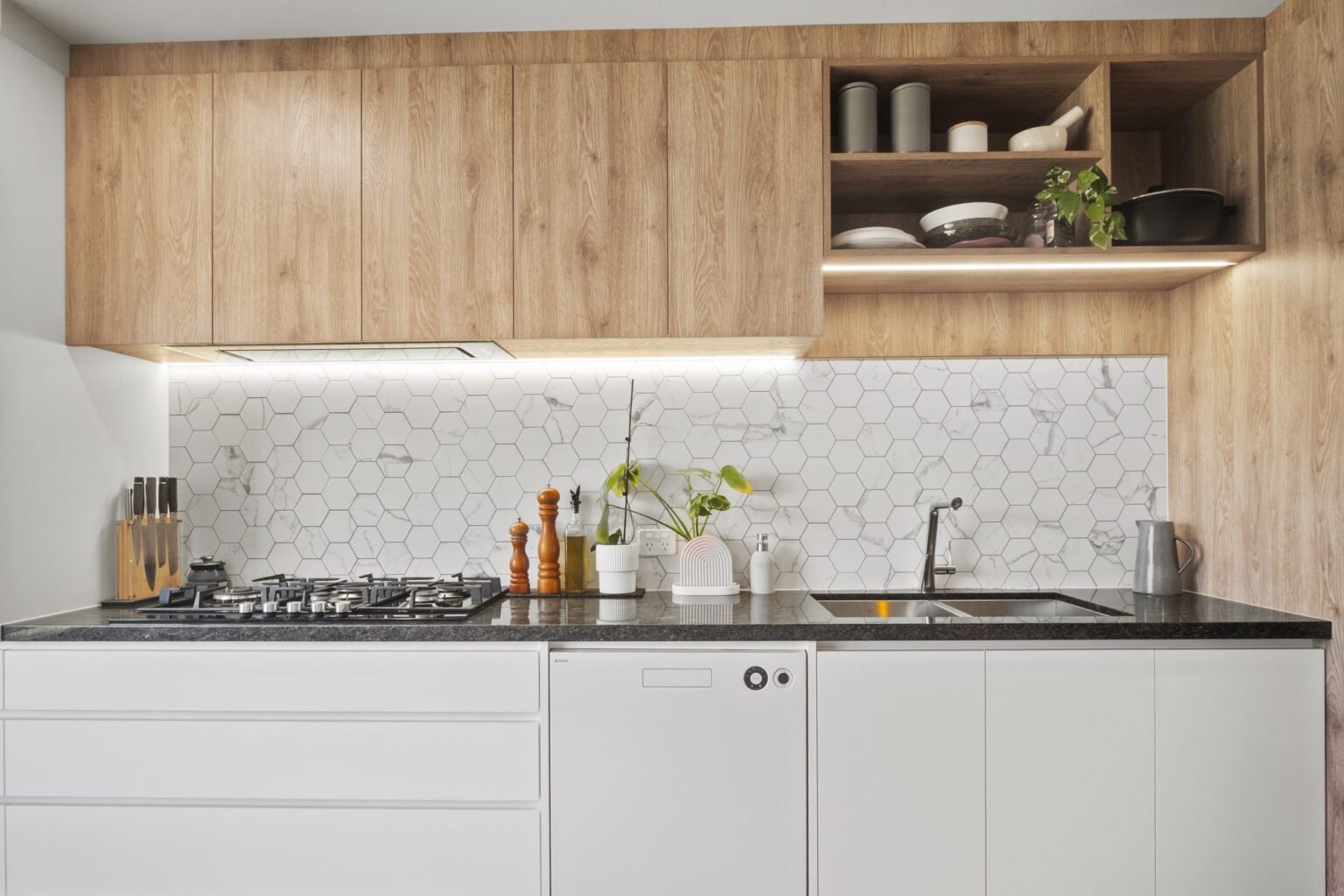 Greenwood kitchen with warm oak overheads, an open shelf and white drawers below the cooking wall