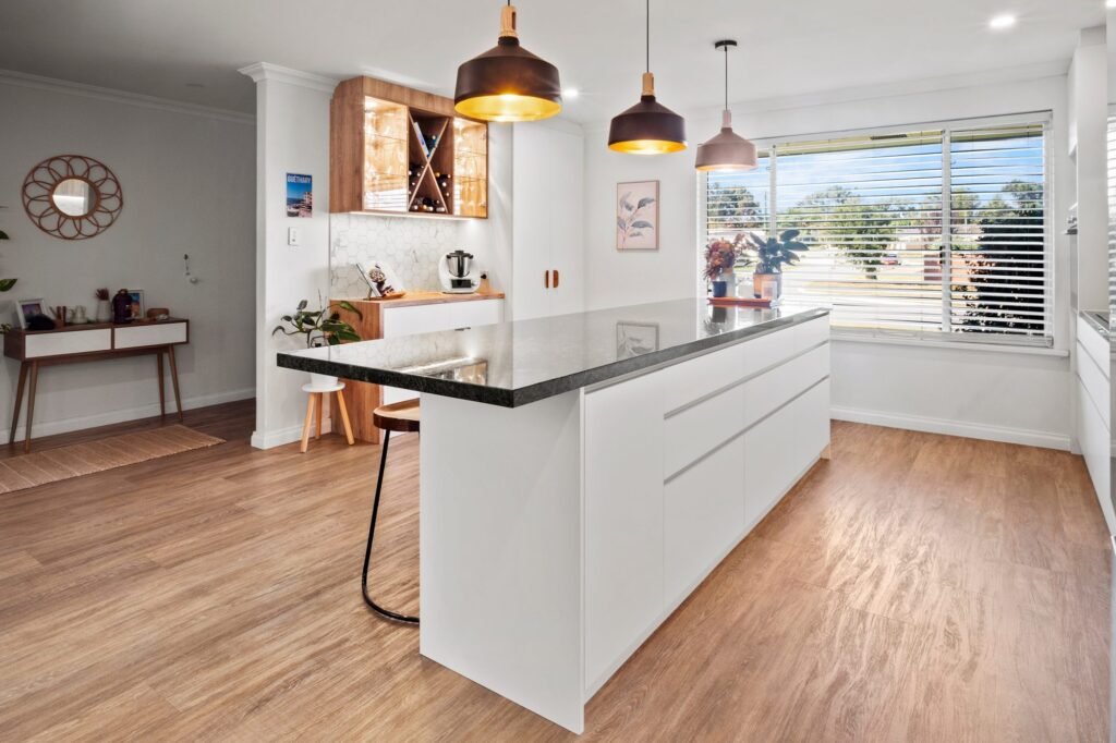 The island end: white end panel, the stone overhanging for one stool, the window wall behind