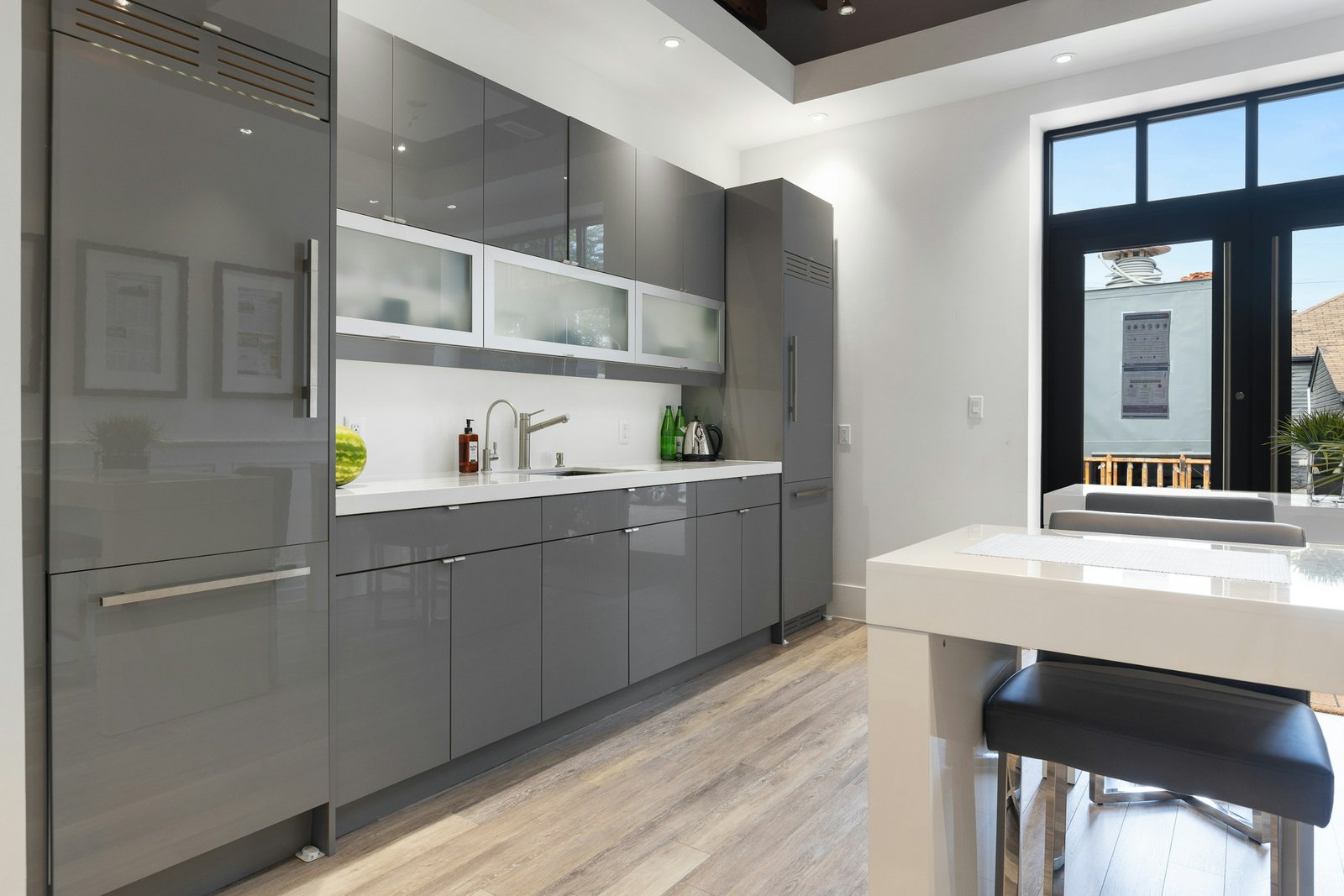 Handle-less grey kitchen with an integrated fridge column and frosted glass uppers