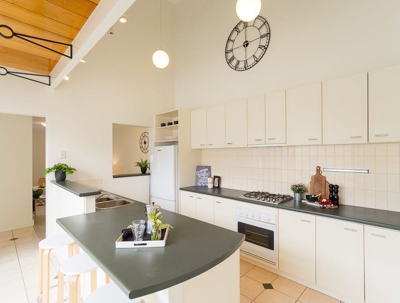 Before: the old North Perth galley from the courtyard end, cream cupboards, dark benchtop, the clock on the wall. Listing photo, 2018
