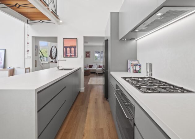 Down the galley toward the living room, the mezzanine walkway overhead