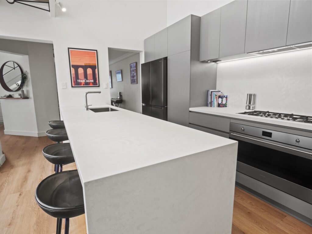 The peninsula with the undermount sink, the gas cooktop and stainless oven on the right-hand wall