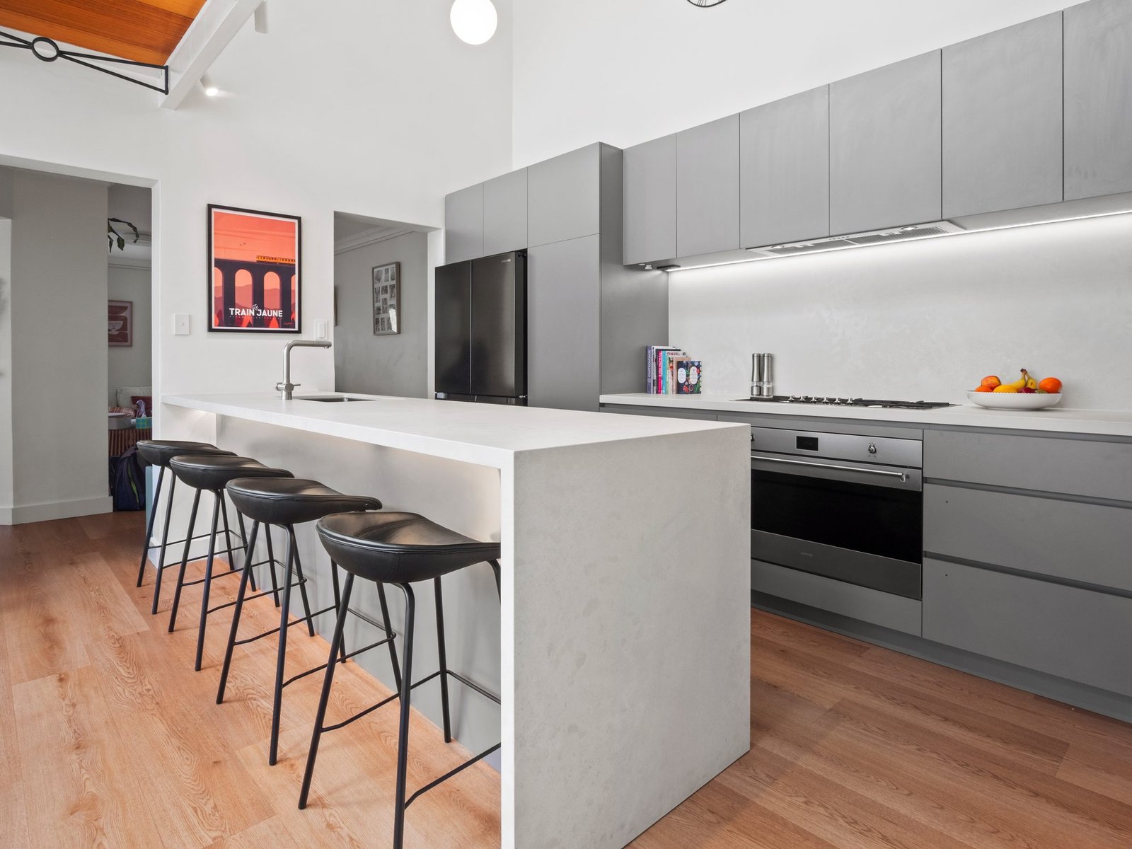 The whole kitchen: grey cabinetry, the peninsula, the mezzanine walkway above