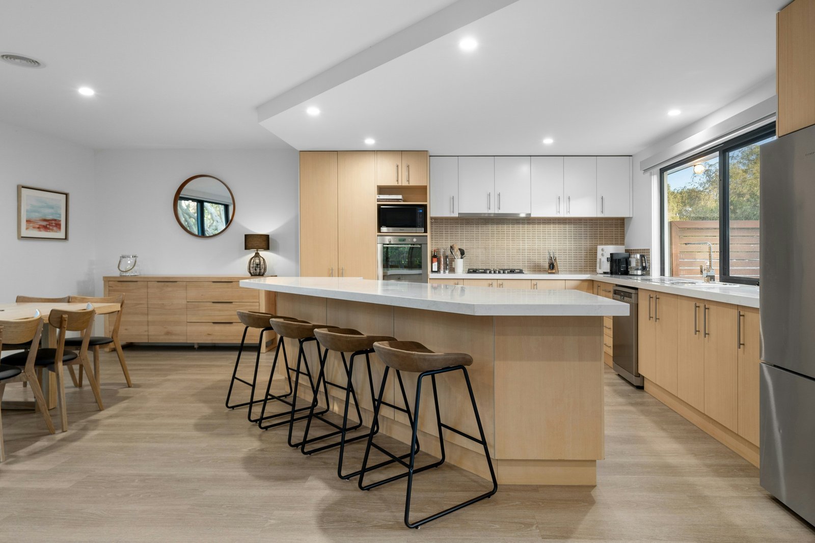 Scandinavian kitchen with pale oak cabinets, white benchtop island and timber stools