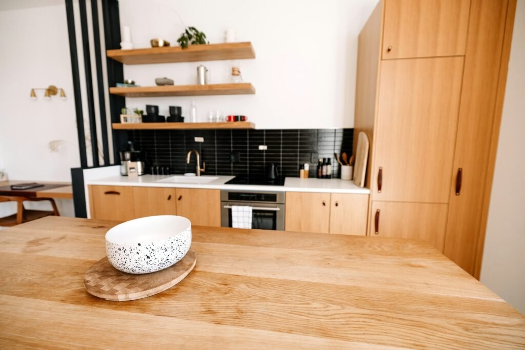 Scandinavian kitchen with oak flat-front cabinets, oak shelves and black tiled splashback
