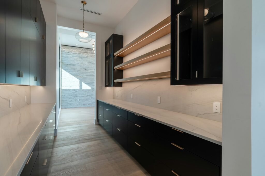 Butler's pantry with dark cabinets, light stone benchtop and timber shelves