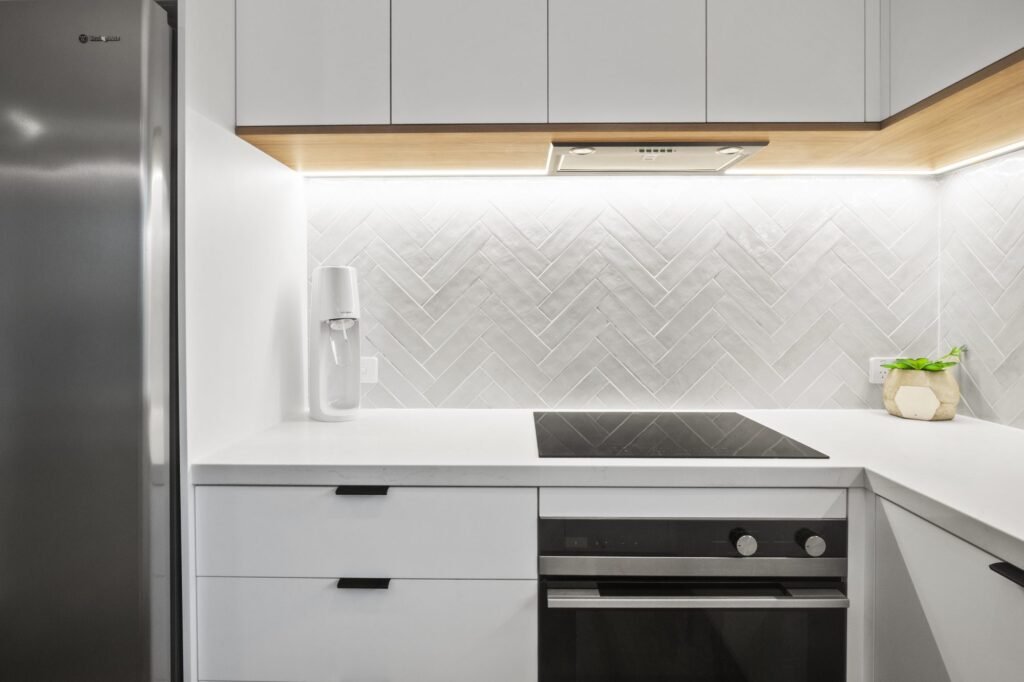 The cooking wall: white overheads with a Boston Oak underside and LED strip, induction cooktop and oven