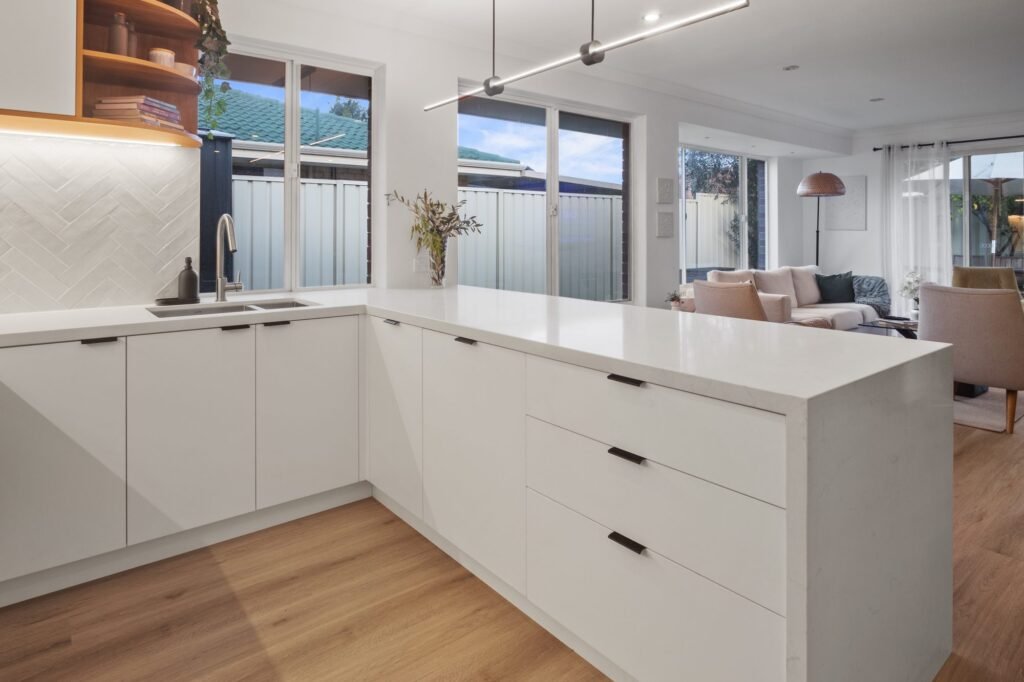 The U from the sink corner: peninsula drawers with black handles and the living room beyond
