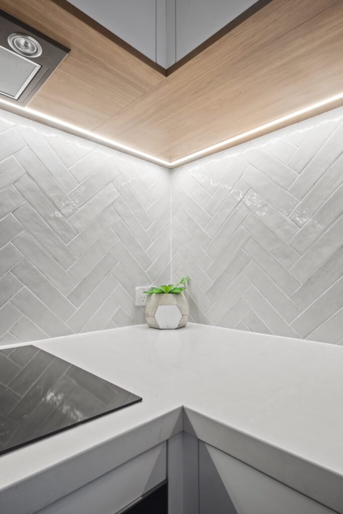 Corner detail: the timber underside of the overheads meeting the herringbone tiles