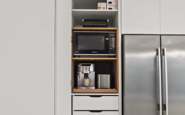 The pantry open: appliance shelf with microwave and coffee machine, custom inner drawers below