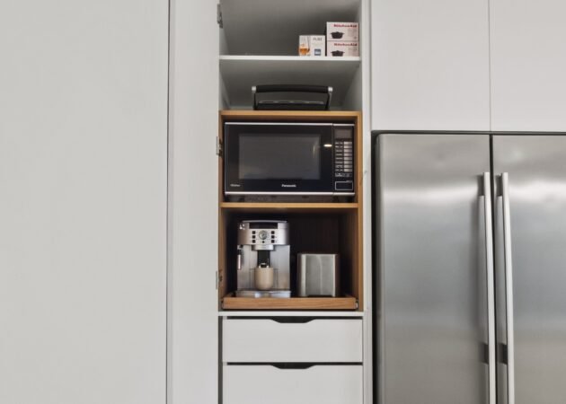 The pantry open: appliance shelf with microwave and coffee machine, custom inner drawers below