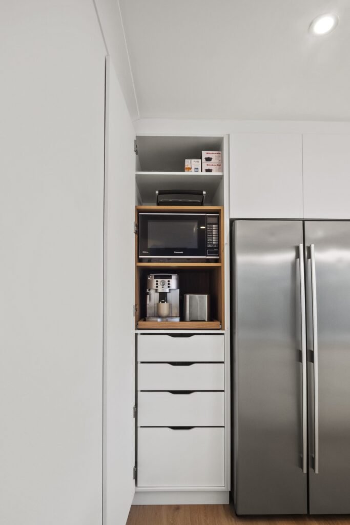 The pantry open: appliance shelf with microwave and coffee machine, custom inner drawers below