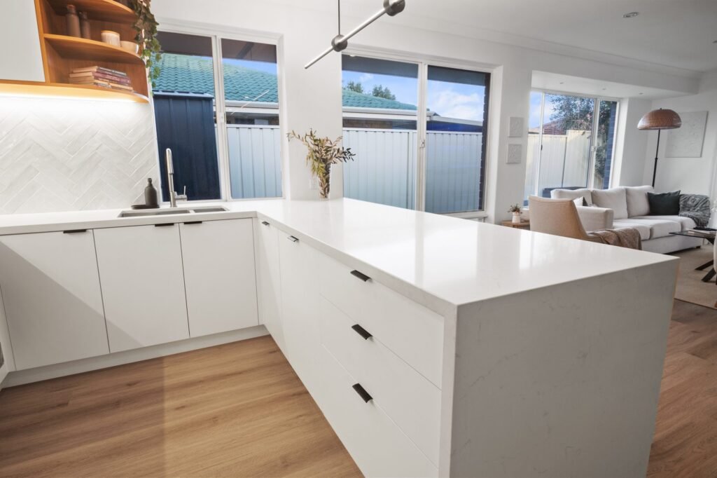 Inside the U: white drawers with black bar handles, the waterfall end, the corner window