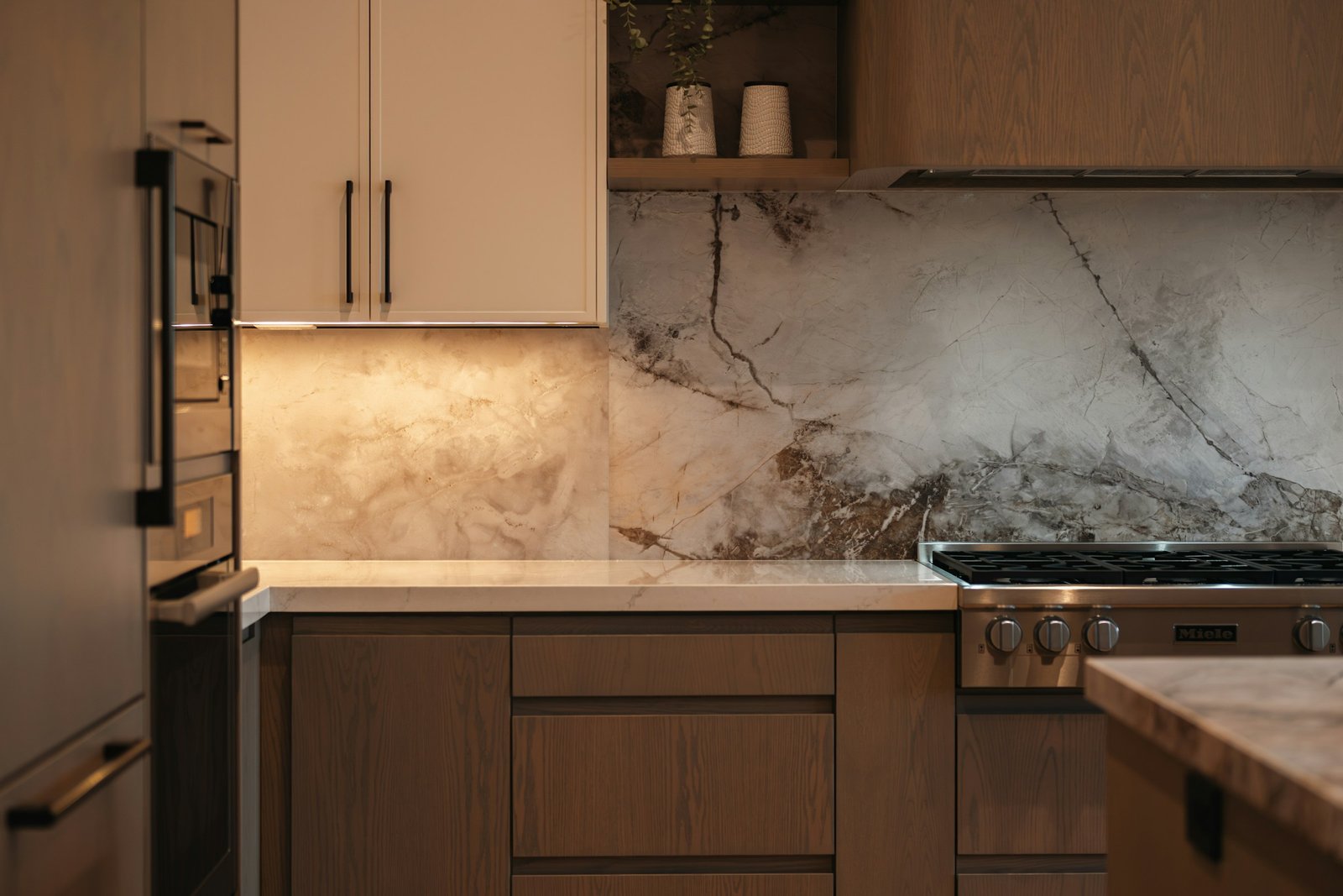 Under-cabinet lighting washing a marble splashback above oak drawers